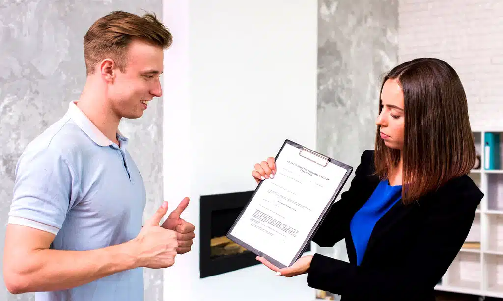 A woman is presenting a clipboard containing a resume to a man