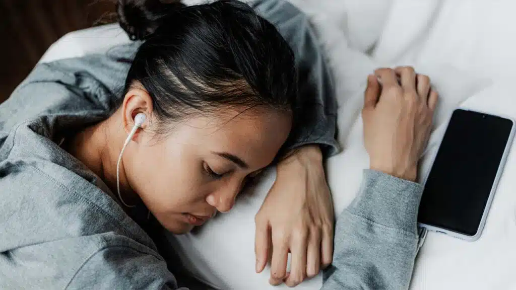 Young woman resting on a bed with earphones in