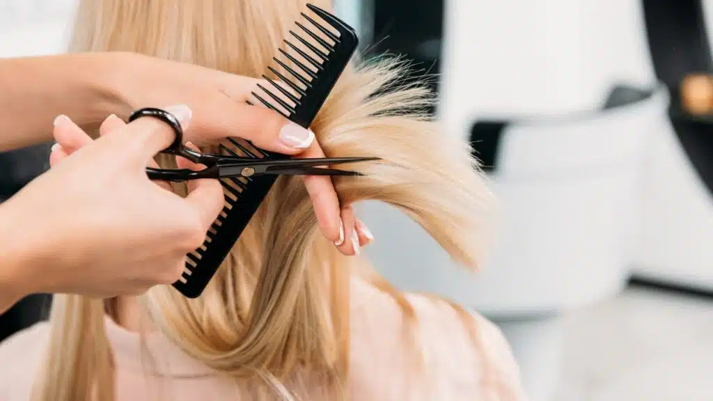 A stylist is trimming a section of blonde hair