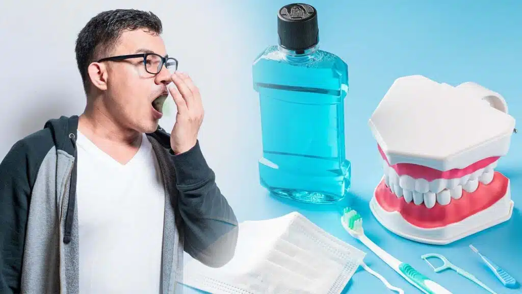 A man checking his breath, next to dental hygiene tools, including a bottle of mouthwash