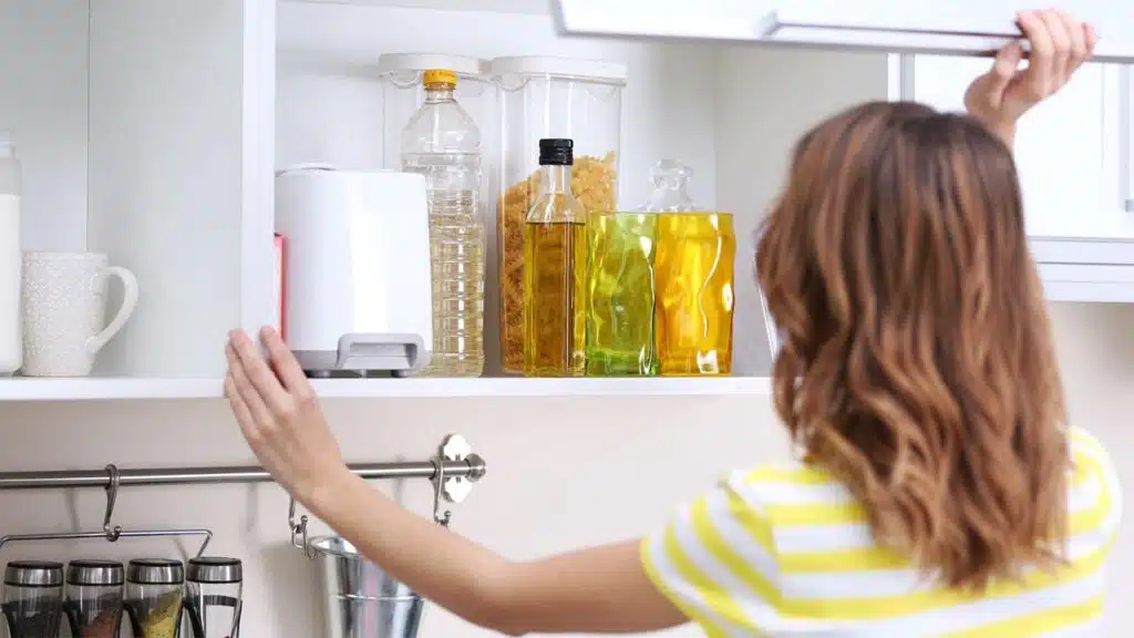 Young woman organizing a kitchen cupboard filled with cooking essentials