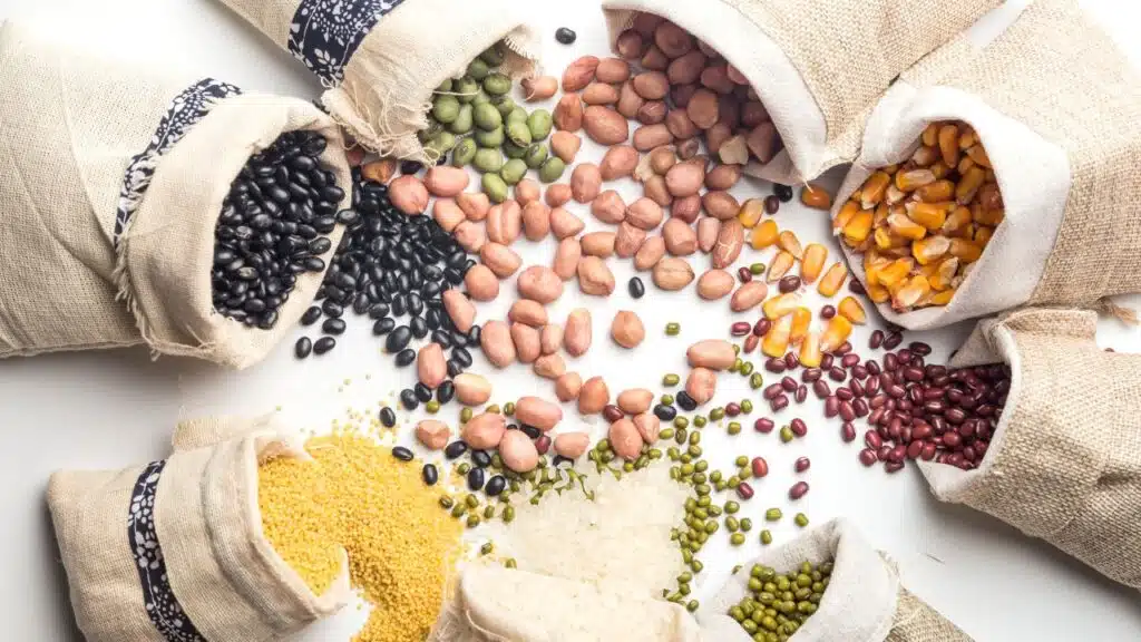 an assortment of various grains, beans, and seeds spilling out from burlap sacks onto a white surface