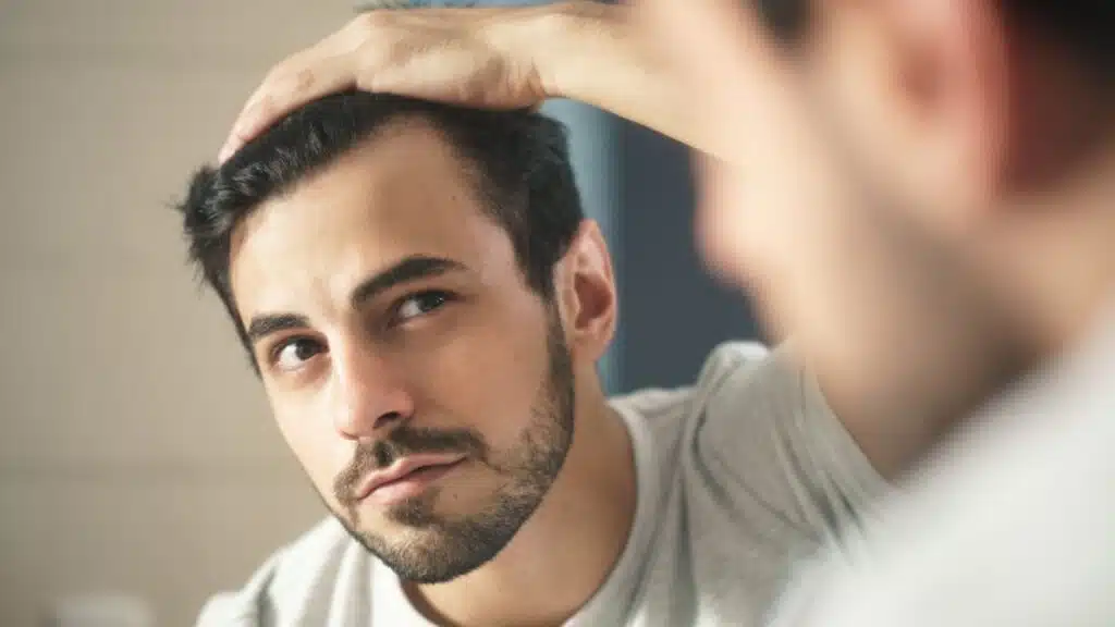 A man looking in a mirror and checking for hair loss