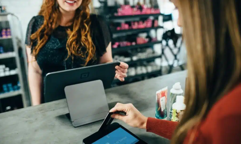 Customer making a payment at a retail counter, showcasing the efficiency of cloud knowledge management software in small businesses.